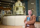 Brought to book: Well-known local journalist Dan Danaher with his book on the people who powered Ardnacrusha, photographed in the machine hall of the power station | PICTURE: John Kelly