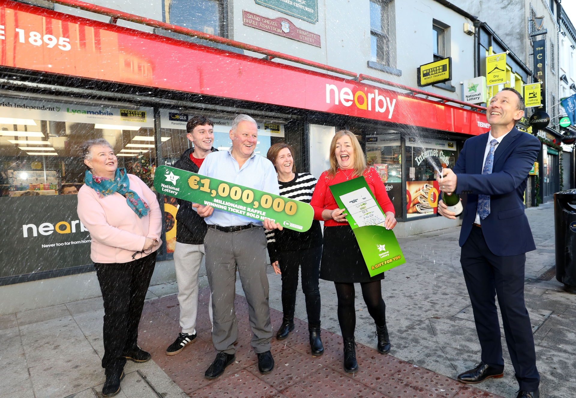 Shop owner Joe Tierney pictured celebrating with staff members, alongside David Woods and Jim O’Connor from the National Lottery| PICTURES: MacInnes Photography