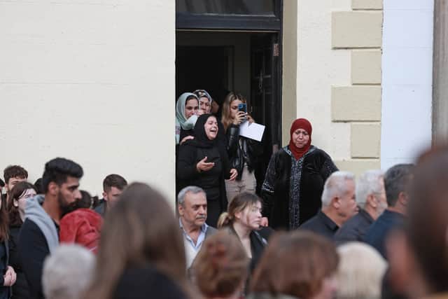 Women stood at the door of the family home and sang a lament as those gathered along the town’s streets stood in silence.