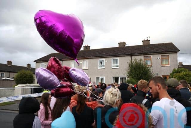 Dozens of bunches of flowers, teddy bears and candles have been placed along the wall as well as photographs of the three, showing Christy and Chelsea making their first Holy Communion.