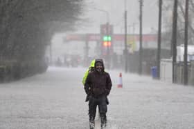 A person walking through floodwater on a pavement